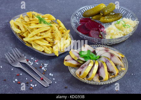 Gesundes Mittag- oder Abendessen mit geräucherter Makrele, eingelegte Gurken, rote Beete, Sauerkraut, Pommes frites auf einem grauen Abstrakt Hintergrund. gesundes Essen. Essen Stockfoto