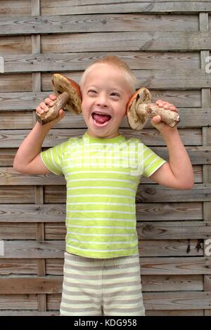 Gerne Jungen mit Down Syndrom, die zwei großen Pilzen. Stockfoto