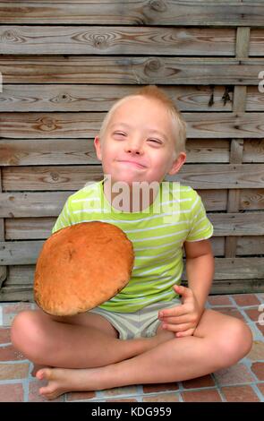 Gerne Jungen mit Down Syndrom eine grosse orange Pilz. Stockfoto