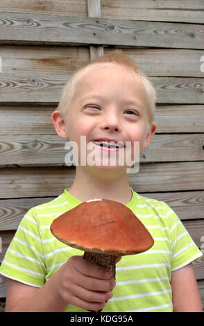 Gerne Jungen mit Down Syndrom eine grosse orange Pilz. Stockfoto