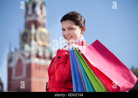 Glückliche junge Frau mit Einkaufstüten zu Fuß auf der Straße Stockfoto