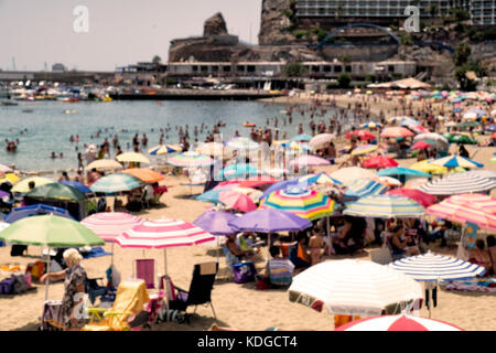 Absichtlich unscharf Bild von Menschen Entspannung und Spaß an einem Strand mit bunten Sonnenschirmen Stockfoto