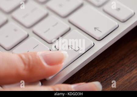 In der Nähe der weiblichen Finger drücken der ENTER-Taste auf der Tastatur Stockfoto