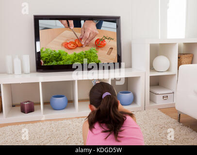 Ansicht der Rückseite des jungen Frau vor dem Fernseher im Wohnzimmer Stockfoto