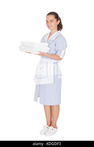 Junge maid Holding Handtücher über weißen Hintergrund Stockfoto