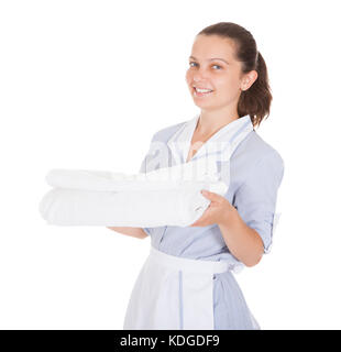 Junge maid Holding Handtücher über weißen Hintergrund Stockfoto