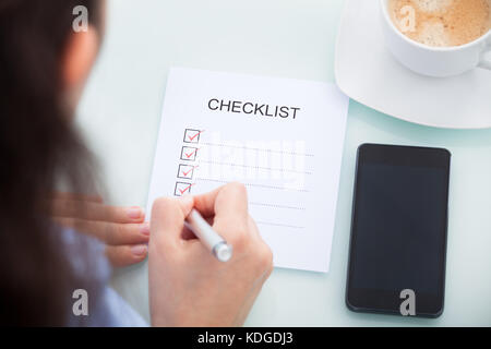 Hohe Betrachtungswinkel und einer geschäftsfrau Markierung auf Checkliste am Schreibtisch Stockfoto