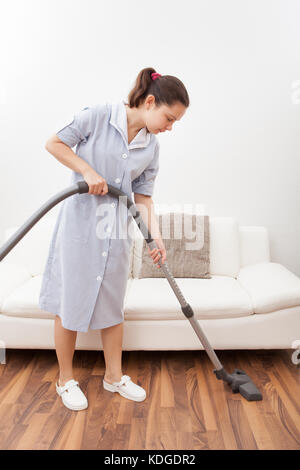 Junge maid Reinigung Boden mit Handstaubsauger Stockfoto
