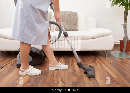 Junge maid Reinigung Boden mit Handstaubsauger Stockfoto