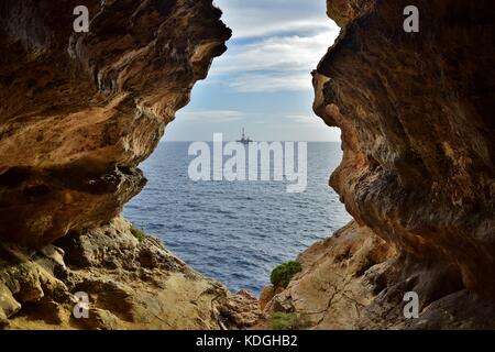 Der Blick vom Meer Höhle, durch Verwitterung und Erosion der maltesischen Kalkstein gebildet. Der Ausgang der Höhle am Meer, mit einer Ölplattform in der Ferne Stockfoto