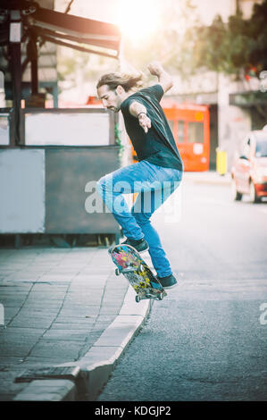 Pro Skater Reiten Skate, macht Tricks und Sprünge auf den Hauptstraßen durch Autos und Stadtverkehr. Free Ride Skateboard Stockfoto