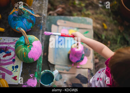 Ein kleines Mädchen malt Kürbisse im Herbst Aktivitäten. Stockfoto