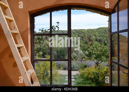 Blick über den Var- oder provenzalischen Wald durch das Gewächshausfenster im Weingut Domaine de Berne, Lorgues, Var, Provence, Frankreich Stockfoto