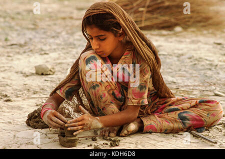 Eine junge sindhi Mädchen, Modelle der Boote von Indus Ton am Ufer des Sees Manchar, Pakistan. Stockfoto