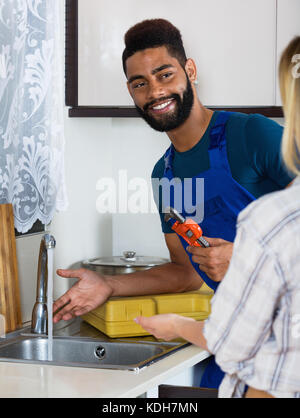 Spezialist für einheitliche Festsetzung tropfenden Wasserhahn, gerne blond lächelnd Stockfoto