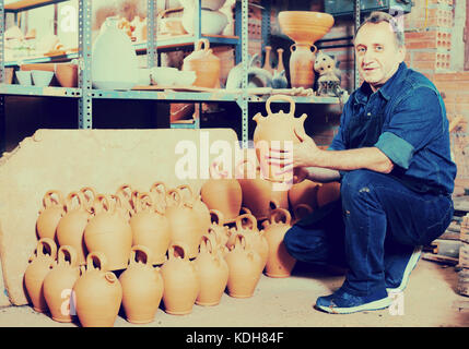 Lächelnd älterer Mann holding Töpferei mit Keramischen Werkstatt Stockfoto