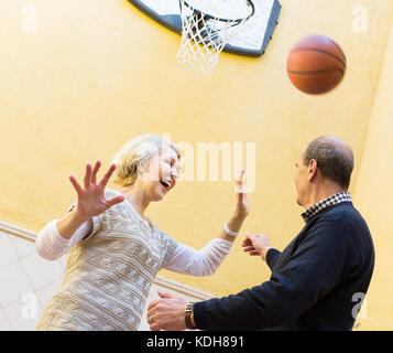 Positiv fröhlichen senior Familie Paar spielen Basketball in Terrasse Stockfoto