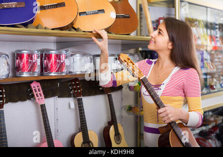 Weibliche Kunden kaufen neue Gitarre im Laden und lächelnd Stockfoto