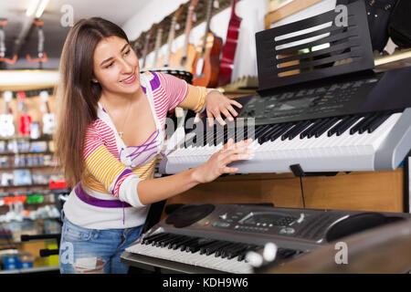 Smiling Happy girl Wahl Synthesizer in der Musik instrumente Shop Stockfoto