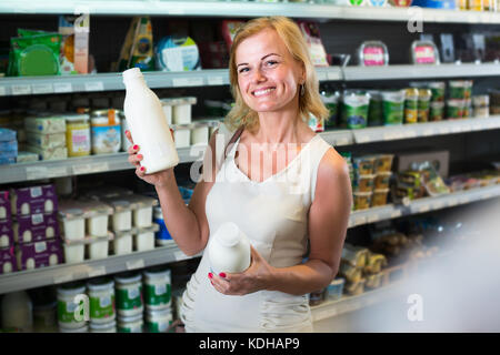 Freundliche weibliche Kunden Auswahl Milch aus dem Kühlschrank in Innenräumen Stockfoto