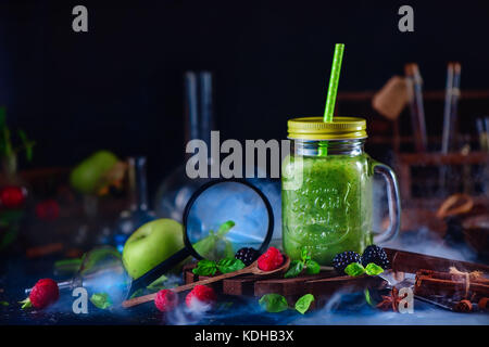 Smoothie jar mit grünen helthy Drink in ein Stillleben mit Beeren, Zimt, Anis, Lupe und Ernährung Laborgeräte. Wissenschaft conce Stockfoto