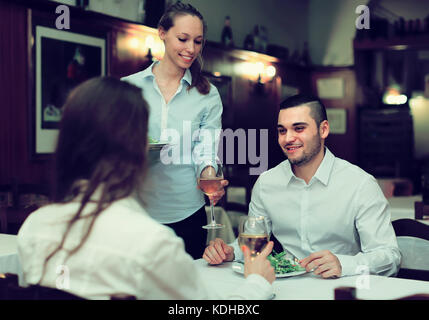 Lächelnd weibliche Kellner bedienen die Gäste Tisch im Restaurant Stockfoto