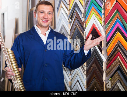 Fröhlicher mann Arbeiter holding Bilderrahmen details zu Counter im Studio Stockfoto