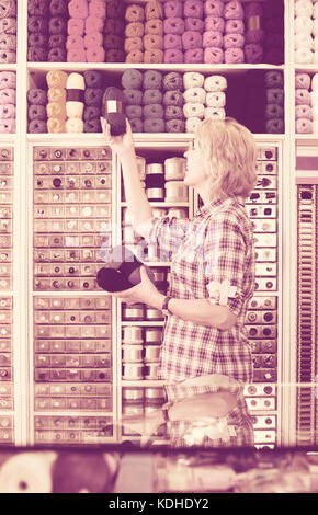 Portrait von Reifen gerne amerikanische weibliche Kassierer an der Kasse in der Stickerei Shop Stockfoto