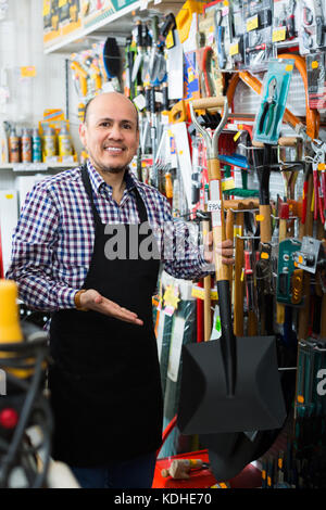 Professionelle senior Verkäufer mit Garten Werkzeuge in Gebäude store Stockfoto