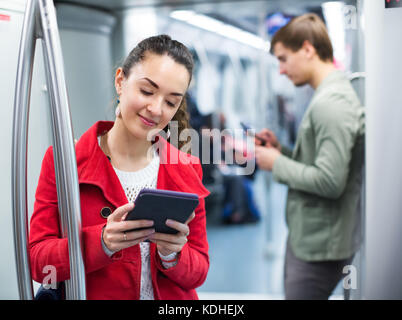 Junge glücklich u-bahn Passagiere besetzt mit modernen Handys und Tablet Stockfoto