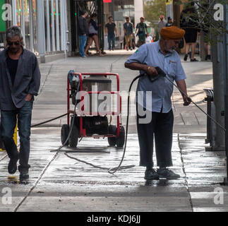 Calgary, Alberta/Kanada – 30. August 2015: Ein Mann, der einen Bürgersteig vor einem Unternehmen in Calgary, Alberta, unter Druck wäscht. Stockfoto