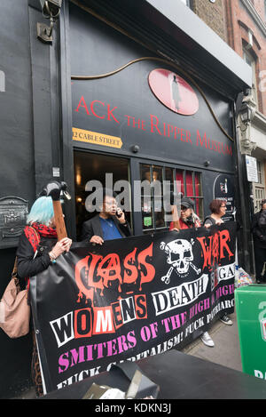 London, Großbritannien. 14. Oktober 2017. Eine Frau aus der Ripper shop legt ihre Hand auf die Klasse Krieg banner außerhalb der sogenannten 'Museum' in Kabel St Anzeige Exponate pries die brutale Serie des 19. Jahrhunderts Morde und ausstellenden Materialien im Zusammenhang mit dem Tod von Frauen aus der Arbeiterklasse. Credit: Peter Marschall/Alamy leben Nachrichten Stockfoto