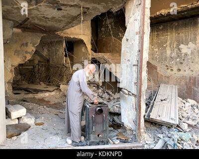 Aleppo, Syrien. Oktober 2017. Abu Subhi macht sich am 12. Oktober 2017 eine Tasse Tee vor seinem Geschäft in Aleppo, Syrien. In den Ruinen der historischsten Souks der Welt betreibt der 62-jährige Abu Subhi ein sehr kleines Geschäft in der Khan al-Harir Straße in der alten Aleppo-Stadt, umgeben von Kriegsverheerungen. Sein kleines Geschäft, in dem er Tischläufer und Tischdecken verkauft, ist das einzige Lebenszeichen in der Jahrhunderte alten Gegend. Quelle: Hummam Sheikh Ali/Xinhua/Alamy Live News Stockfoto