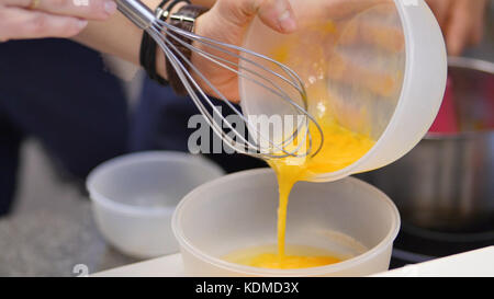Eigelb mit Zucker in einer Glasschale. Verprügelte Eigelb in einer Schüssel mit Schneebesen. Verschlagenes Eigelb Stockfoto