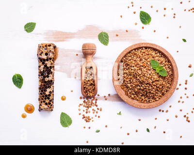 Raw organic Biene Blütenstaub auf schäbige Holzbrett. Biene Blütenstaub Granulat und Propolis in Holz- Schaufel. Homöopathische essen Konzept mit Biene Blütenstaub mit pepperm Stockfoto