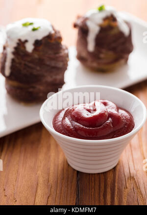 Tomatensauce mit gebackenen Kartoffeln mit Speck umwickelt Stockfoto