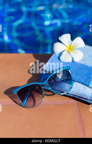 Flauschige Handtuch mit Sonnenbrille und Blume an der Grenze von einem Pool - Urlaub tropische Konzept Stockfoto