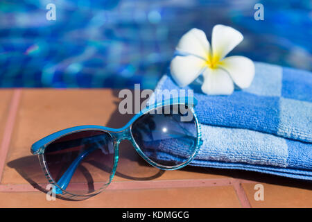 Flauschige Handtuch mit Sonnenbrille und Blume an der Grenze von einem Pool - Urlaub tropische Konzept Stockfoto