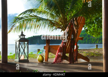 Liegestuhl im Bungalow Terrasse bei Sonnenuntergang in Luxury Beach Hotel auf der tropischen Insel mit Kokosnuss trinken. Stockfoto