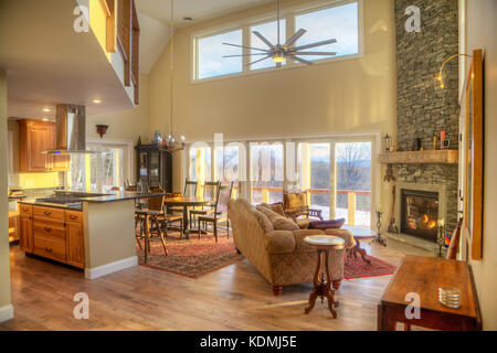 Modernes, schickes Wohnzimmer mit angrenzender Küche, Esszimmer und Kamin aus Stein in Vermont, USA. Stockfoto