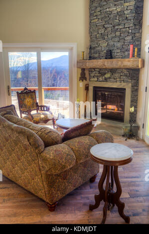 Modernes, schickes Wohnzimmer mit angrenzender Küche, Esszimmer und Kamin aus Stein in Vermont, USA. Stockfoto