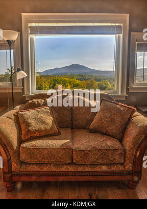 Tiefe, komfortable Viktorianische Liebe Sitz vor einem Fenster mit Mount Ascutney im Hintergrund. Hartland, VT, USA. Stockfoto