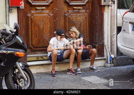 Nizza, Frankreich, 15. August 2017: undefiniert Teenager mit Handy auf dem Treppenabsatz vor dem Haus Stockfoto