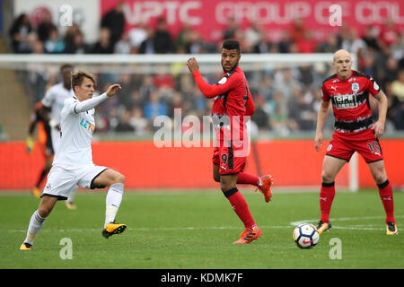 Elias Kachunga aus Huddersfield Town (Mitte) und Tom Carroll aus Swansea City (links) kämpfen um den Ball während des Premier League-Spiels im Liberty Stadium in Swansea. Stockfoto