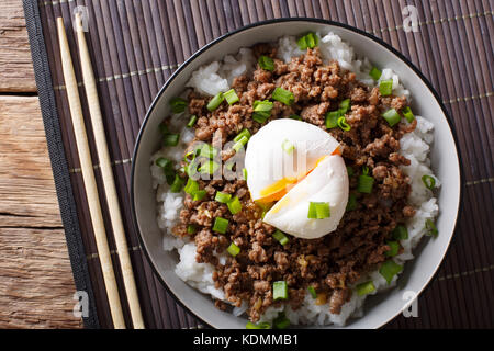 Japanische Gerichte: würzige Fleisch soboro mit pochiertem Ei und Reis close-up in einer Schüssel auf den Tisch. horizontal oben Ansicht von oben Stockfoto