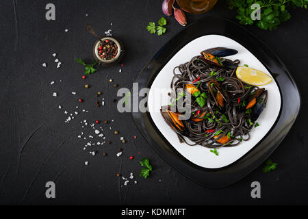 Schwarze Spaghetti. schwarz Meeresfrüchte Pasta mit Miesmuscheln über schwarzen Hintergrund. Mediterrane Delikatesse essen. Flach. top View Stockfoto