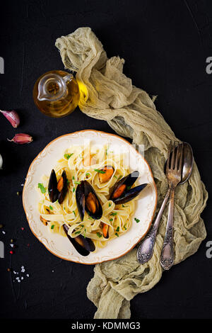 Fisch Fettuccine Pasta mit Miesmuscheln über schwarzen Hintergrund. Mediterrane Delikatesse essen. Flach. top View Stockfoto