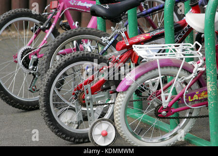 Eine Reihe von Fahrräder, Kinder Erwachsene, die im Zyklus Regalen gesäumt. Bike Rack. Stockfoto