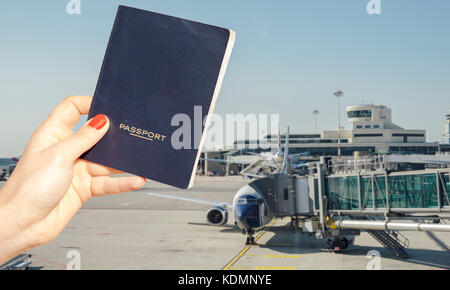 Digital composite von Hand mit einem generischen Reisepass mit hektischen Airport Terminal in verschwommenen Hintergrund Stockfoto