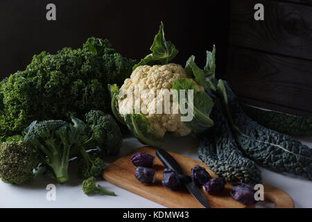 Noch immer leben von verschiedenen Arten von Kohl auf dem Tisch: lacinato Kale, blau geringelt vates Grünkohl, Blumenkohl, Rosenkohl ende Brokkoli. Stockfoto